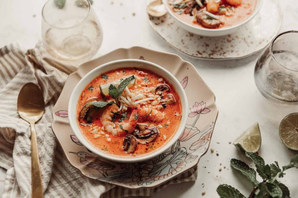 Shrimp mushroom tomato soup garnished with mint, served in a pink floral bowl